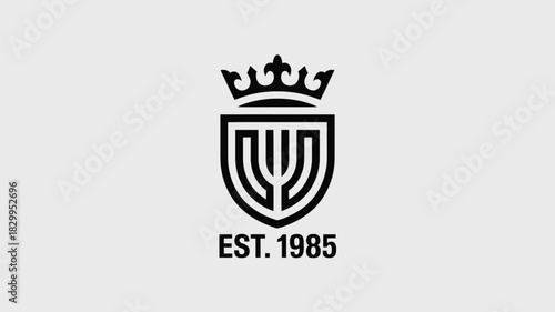 A black and white logo featuring a crown and a shield with the text est one thousand nine hundred eighty five