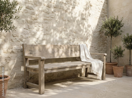 Wooden bench with blanket in a sunlit courtyard with olive trees