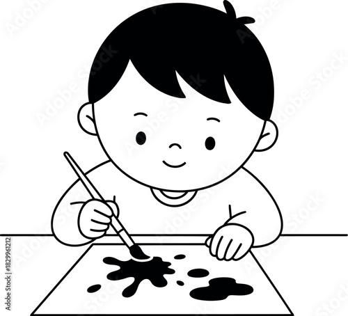 Young boy happily painting with a brush on paper