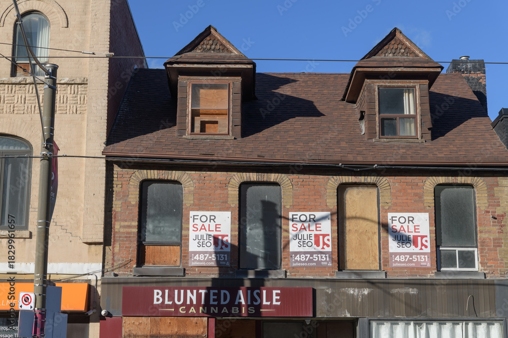 Fototapeta premium historic building facade with for sale signs and Blunted Aisle Cannabis ghost display at 668 Queen St E, Toronto