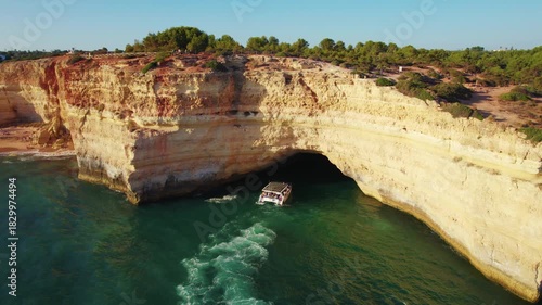 Aerial of a boat coming out of a Benagil cave in southern coast of Portugal