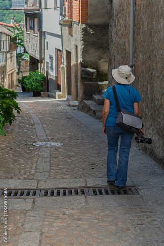 Female tourist seen from behind photographing the streets of the villages of the Sierra de Francia (Salamanca, Spain) in summer