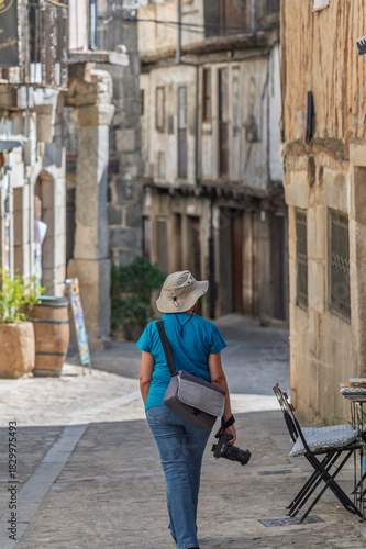 Female tourist seen from behind photographing the streets of the villages of the Sierra de Francia (Salamanca, Spain) in summer