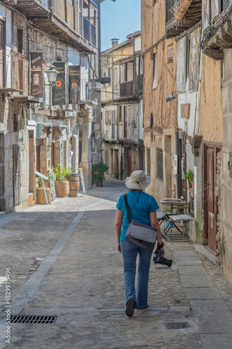 Female tourist seen from behind photographing the streets of the villages of the Sierra de Francia (Salamanca, Spain) in summer