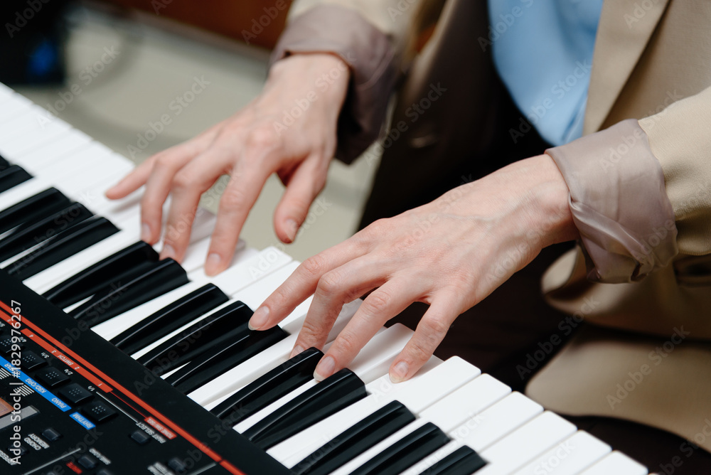 Fototapeta premium female pianist hands on black and white synthesizer keyboard, close-up view, young woman playing piano, professional musician