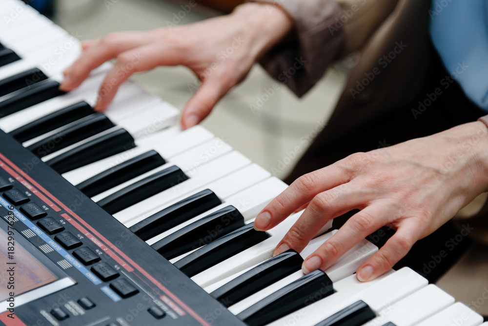 Fototapeta premium female pianist hands on black and white synthesizer keyboard, close-up view, young woman playing piano, professional musician