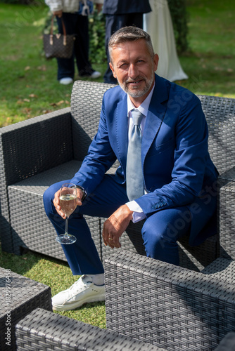 Elegant man in blue suit relaxing outdoors with a glass of wine