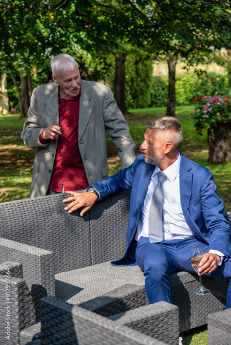 Two men talking outdoors during a formal event