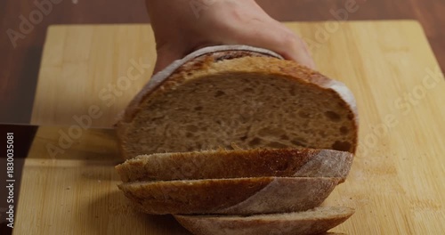 Slicing Wholegrain Bread Cri On Slice For Bruschetta. Cutting Sourdough Bread On Kitchen. Making Morning Toast Breakfast.Fresh Crisp Sourdough Bread On Table. Cutting French Multigrain Bread For Toast