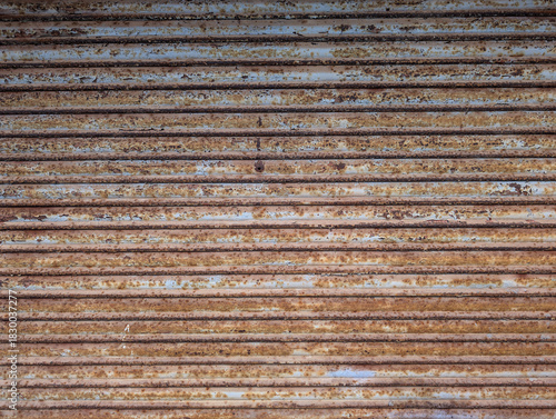 Frame texture of old rusted and peeling metal roller garage shutter door. Rust, oxidation, paint patches, distressed, textured industrial surface, decay, urban grit, deterioration, corrosion. 