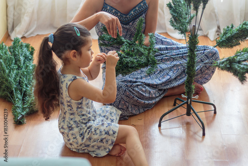 Madre e hija armando y decorando un árbol de Navidad