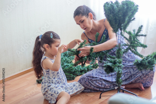 Madre e hija armando y decorando un árbol de Navidad