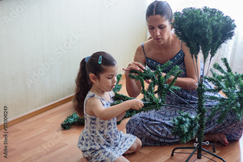 Madre e hija armando y decorando un árbol de Navidad