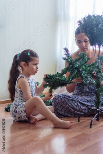 Madre e hija armando y decorando un árbol de Navidad