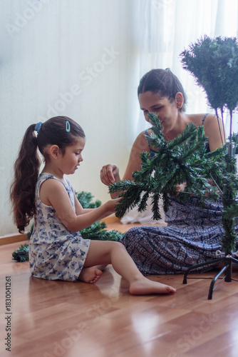 Madre e hija armando y decorando un árbol de Navidad