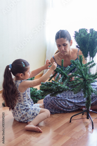 Madre e hija armando y decorando un árbol de Navidad