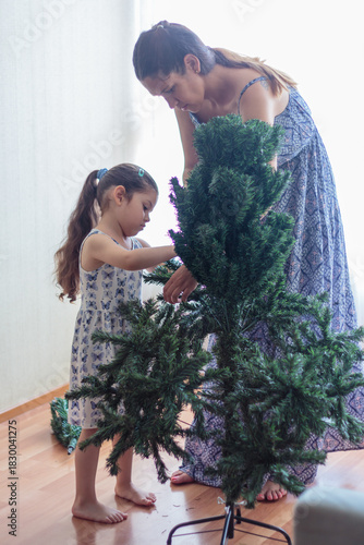 Madre e hija armando y decorando un árbol de Navidad