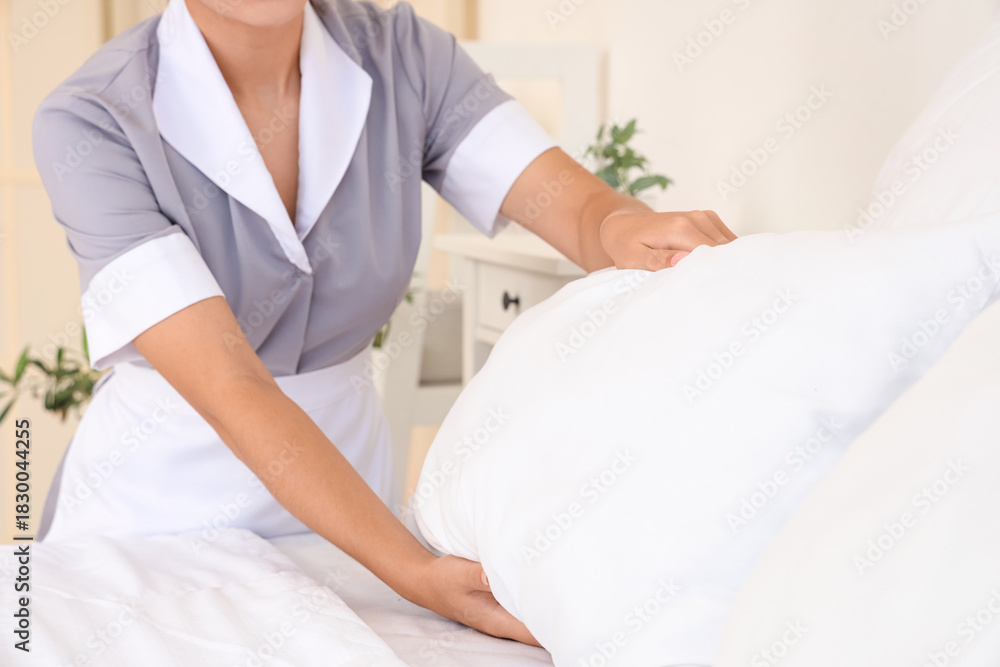 Fototapeta premium Chambermaid making bed in hotel room, closeup