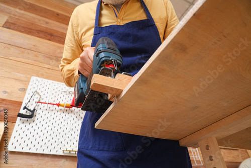 Mature carpenter sawing woo...