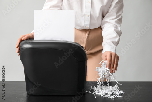 Quadro em tela Secretary destroying document in shredder on light background