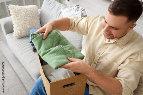 Young man packing folded cl...