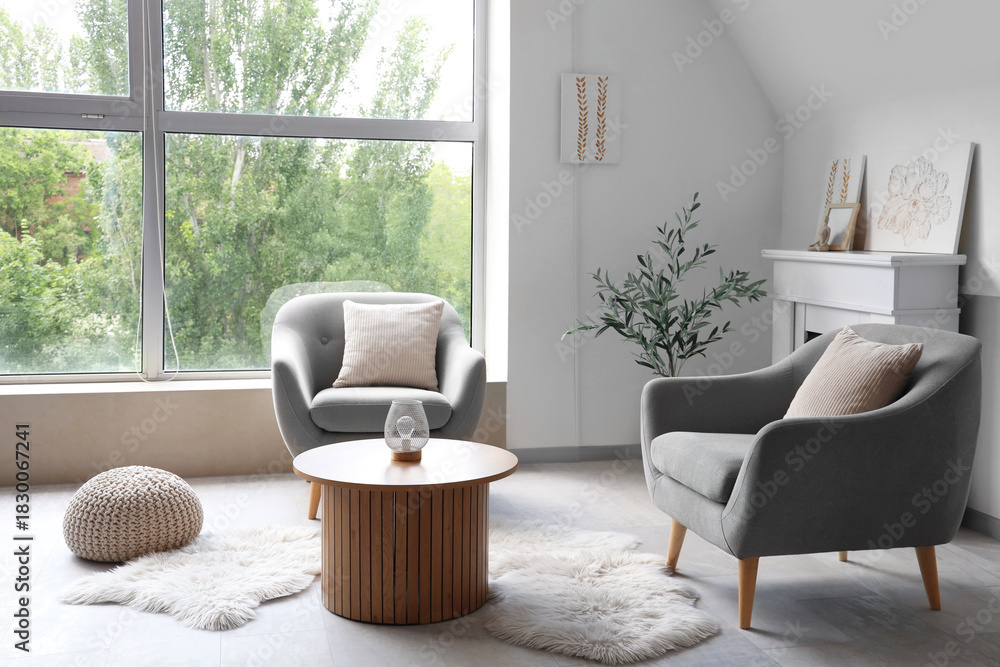 Fototapeta premium Interior of light living room with paintings, fireplace and armchairs