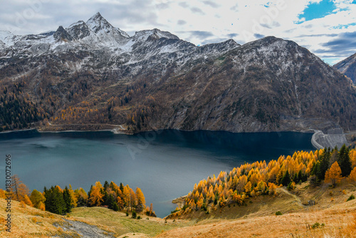 Autumn landscape with orange colored trees, view from above of a high mountain lake, in November