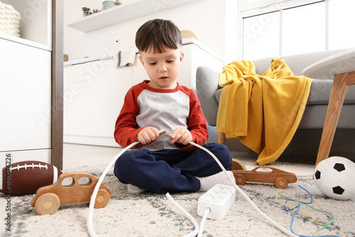 Fotografía Little boy with bare wire in kitchen. Child at risk