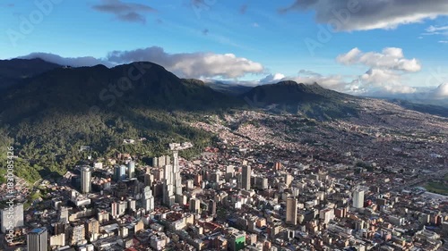 Dynamic aerial view panning right toward the sun setting over the bustling urban landscape of Bogotá, Colombia, with the majestic Andes mountains in the background
