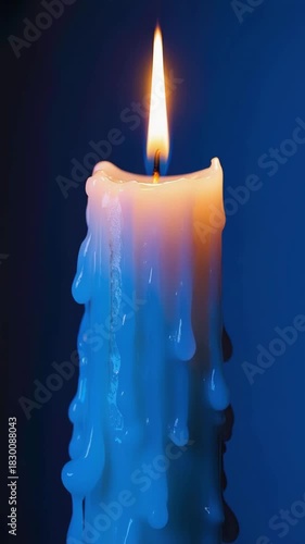 Close-up of a burning candle with melting wax on a blue background