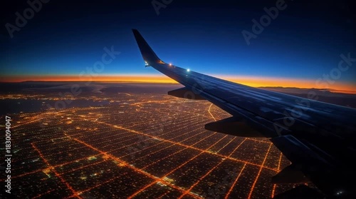 POV Aerial View from Airplane Window Over a Night Cityscape with Wing Silhouette