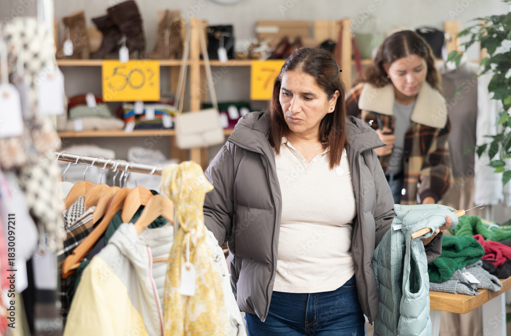 Obraz premium Female shopper selects some fall winter outerwear at a clothing store