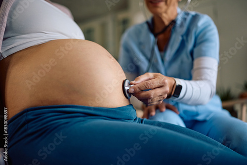 Close up of obstetrician using stethoscope during prenatal check-up of a pregnant woman.