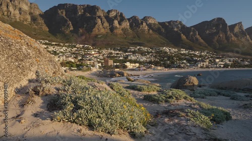 Breathtaking panoramic view of Camps Bay’s white sandy beaches and Atlantic Ocean, framed by the majestic Twelve Apostles mountains in Cape Town, Western Cape, South Africa. Captured in 4k 60p.