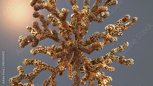 Glamorous golden christmas tree ornament encrusted with glitter slowly rotating against warm backlit gray, creating elegant bokeh, shimmer and festive holiday sparkle