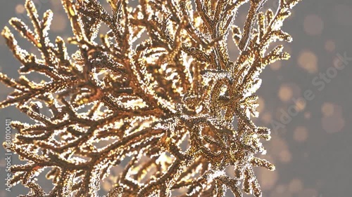 Elegant golden branch covered with ice crystals rotating against a shimmering background with bokeh lights, creating a festive and luxurious atmosphere for winter holidays celebrations