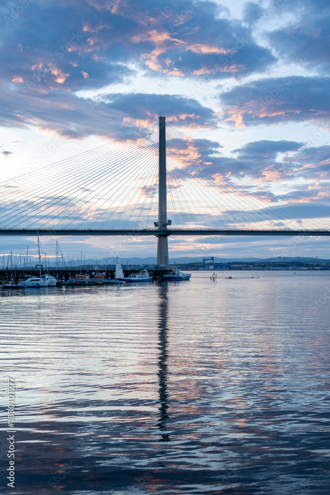 Obraz premium An evening photo of the Queensferry Crossing over the Firth of Forth, with reflections and a blue glow.