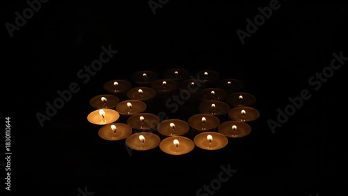 Circle Arrangement Of Lit Tea Light Candles Emitting Warm Orange Glow With Wisps Of Smoke Against A Dark Moody Background And Rustic Wooden Surface With Dramatic Lighting Creating An Atmosphere Of
