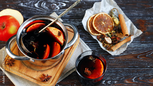 Homemade mulled wine in a ladle, spices, oranges and apples