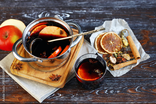 Homemade mulled wine in a ladle, spices, oranges and apples