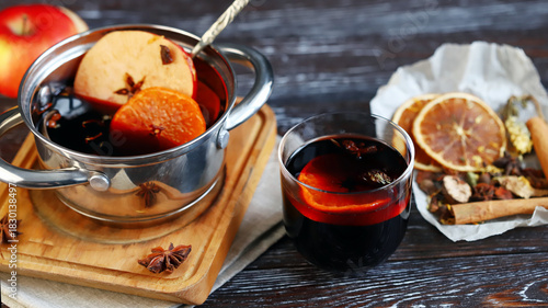 Homemade mulled wine in a ladle, spices, oranges and apples