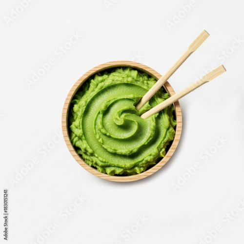 Spicy wasabi paste in bowls with wooden chopsticks resting beside viewed from top, ideal for sushi and asian food themes