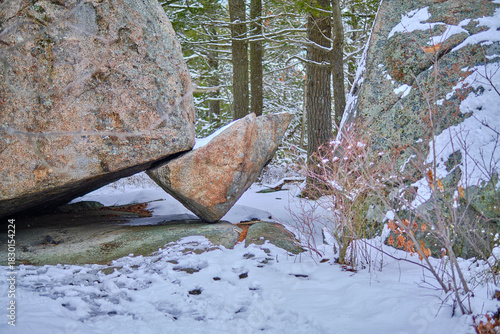 Foto Large boulder balancing on a small rock covered in snow.