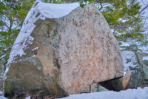 Bilde på lerret Large boulder balancing on a small rock covered in snow.