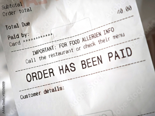 Restaurant receipt closeup detail with “order has been paid” text and allergen info, takeaway delivery bill on thermal paper showing total due, card payment confirmation, printed checkout slip, nobody