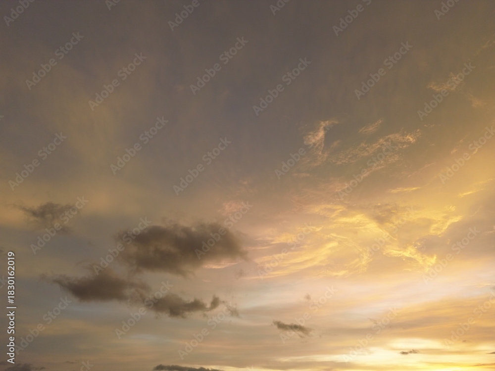 Fototapeta premium Warm glowing sunset sky with soft textured clouds and subtle color gradients. Peaceful atmospheric view perfect for background and nature visuals.