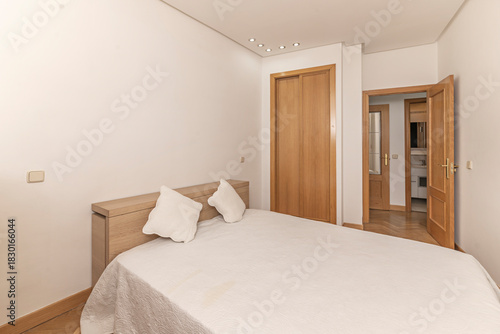 Minimalist bedroom with a 140cm bed with a leather headboard, articulated wall lamps, and a frameless circular mirror