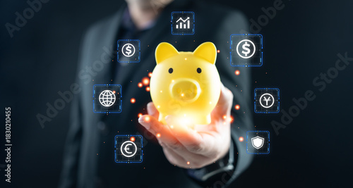 Businessman hand hold a glowing yellow piggy bank surrounded by virtual finance icons. Concept of digital savings, FinTech investments, and personal wealth management