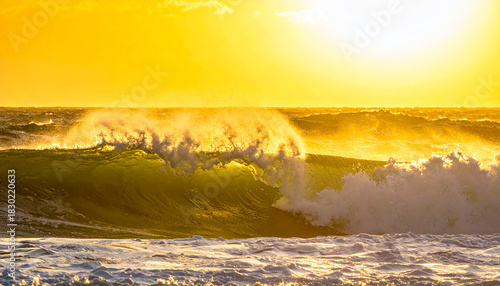 Fototapeta Naklejka Na Ścianę i Meble -  Bright yellow sun over a powerful ocean wave breaking at sea water surf
