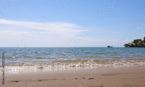 Tropical Beach Scene with Gentle Waves and Distant Boat on a Sunny Day